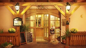 Une entrée en bois, avec une porte en verre, une horloge et une statue.