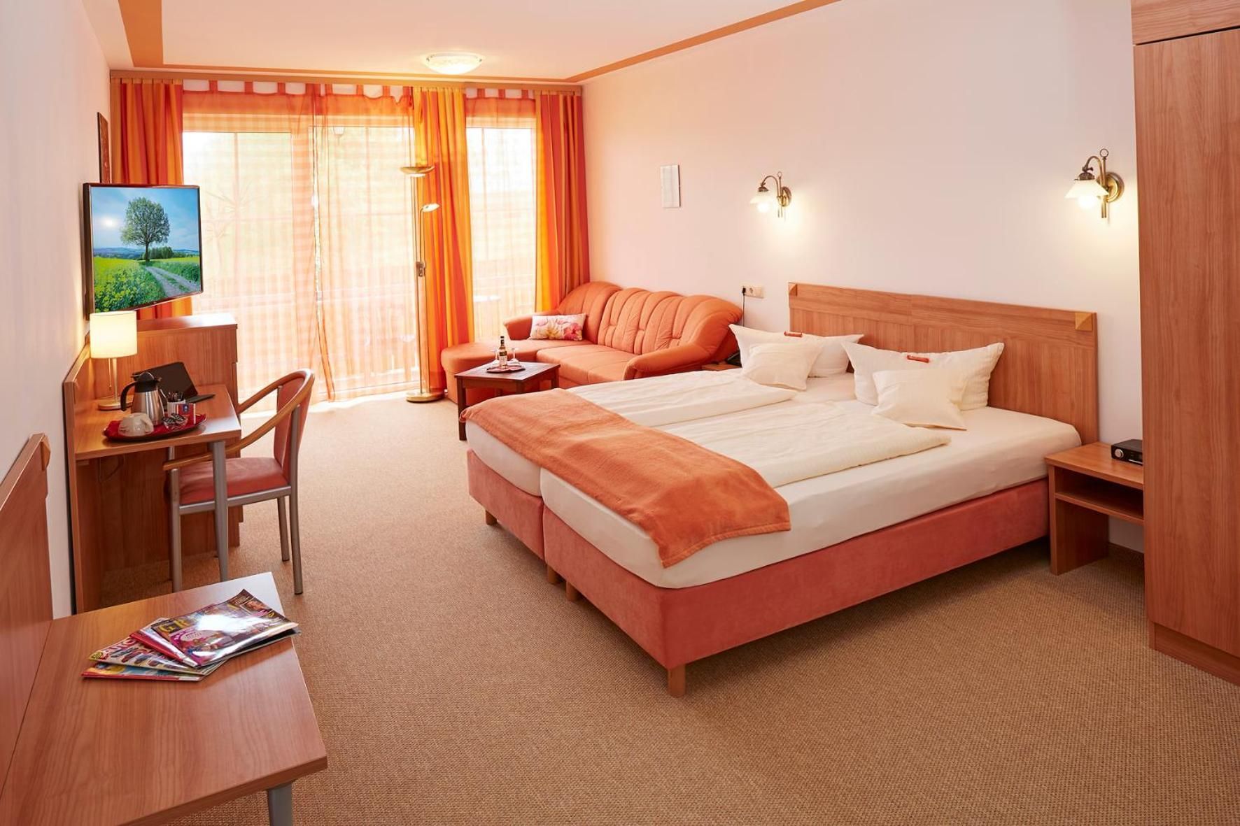 Een hotelkamer met een bed, bureau, stoel, televisie en raam met gordijnen.