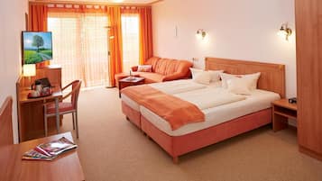 Een hotelkamer met een bed, bureau, stoel, televisie en raam met gordijnen.