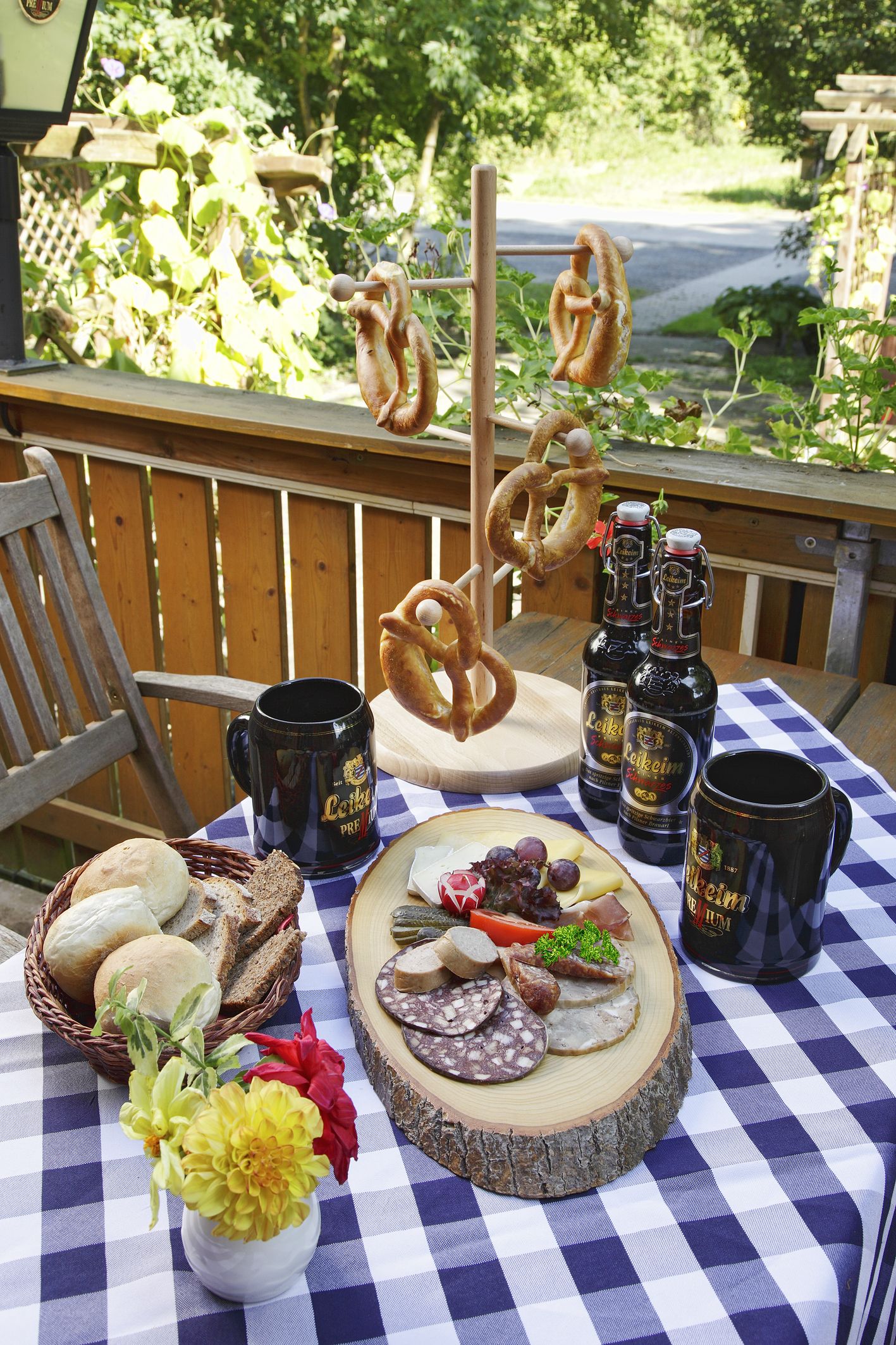 En picknickuppsättning med kringlor, ölflaskor, en ostbricka och ett rutigt bordstycke.