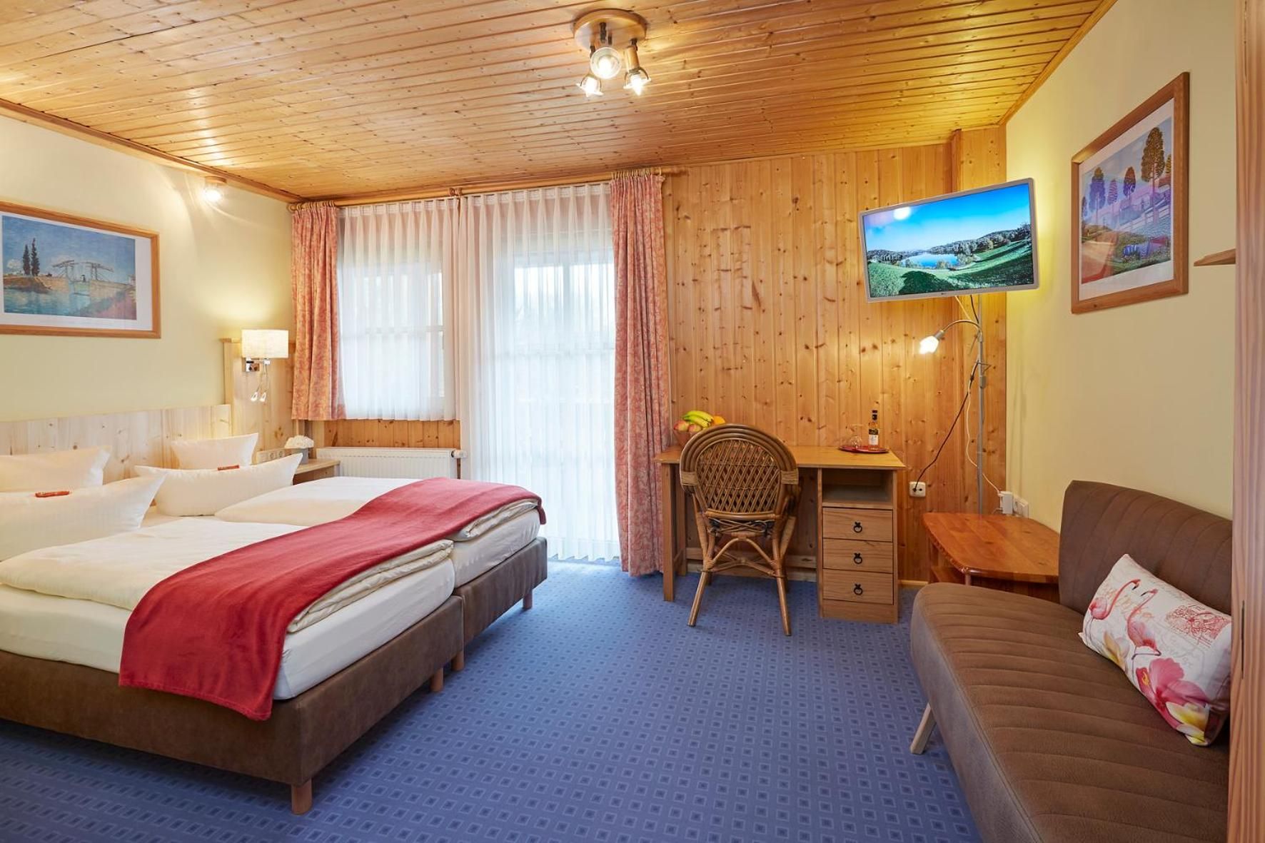 Habitación de hotel con cama, escritorio, silla, sofá y televisión.