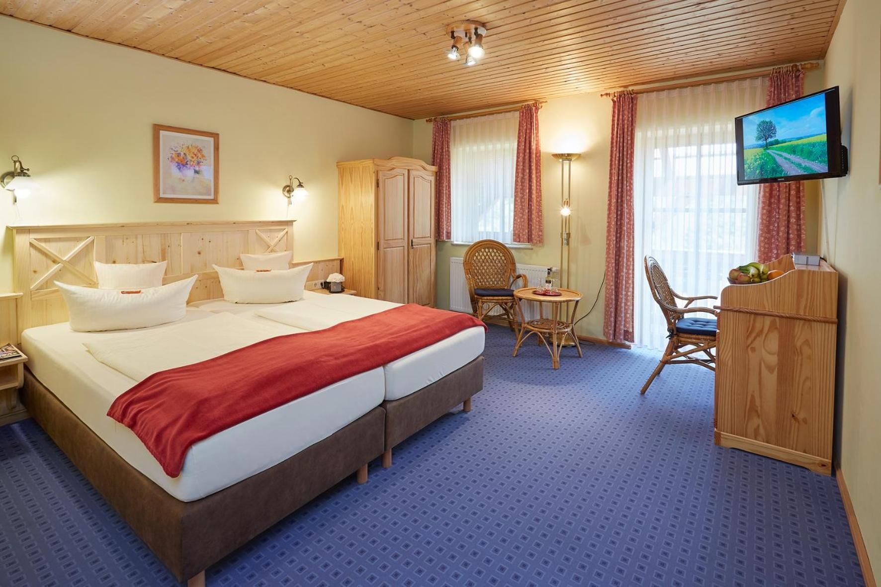 Una camera d'albergo con un letto grande, una scrivania, una sedia, un televisore e un armadio.