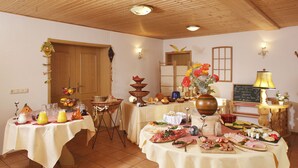 Un espace repas avec plusieurs tables dressées pour un repas, où l’on peut voir une variété de plats et une pièce décorative au centre.