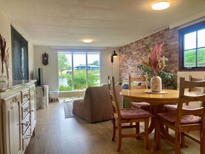 Un comedor acogedor con pared de ladrillo, un ventanal y vistas al exterior con vegetación.