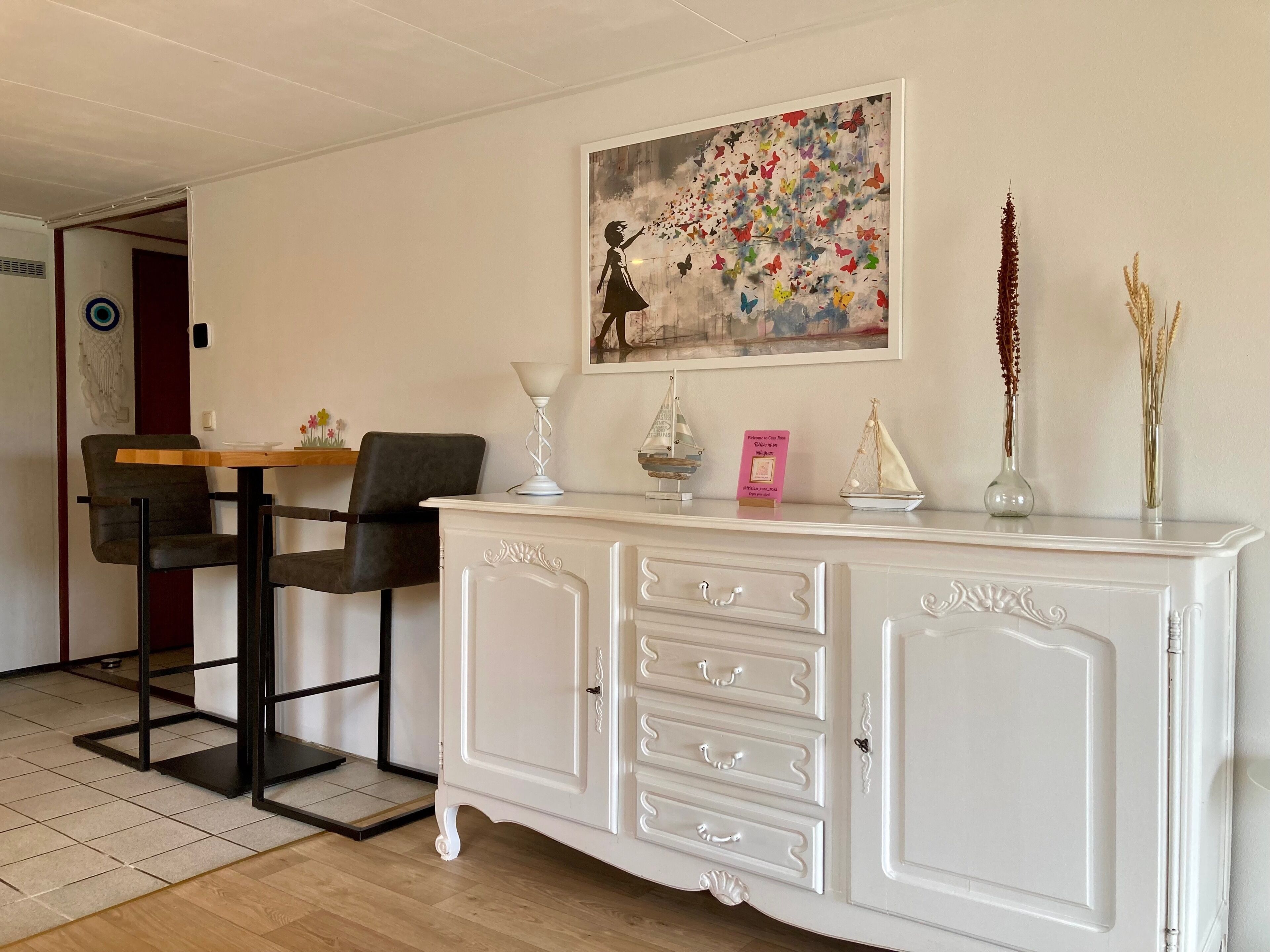 Un comedor con un armario blanco, un cuadro y objetos decorativos.