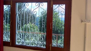 Una ventana con rejas de hierro decorativas y vistas al verdor exterior.