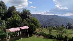 Zona verde con un toldo a rayas rojas y blancas y vistas de una cordillera.