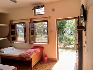 A room with a bed, a window, a television, and a door leading outside. - StayApart - Maa Anadmayee Guest House (Almora)