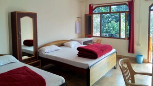 Una habitación de hotel con dos camas, un escritorio, una silla, un espejo y una ventana con cortinas.
