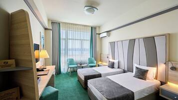 A hotel room with two beds, a desk, a chair, and a small table.