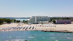 Un hôtel doté d’une grande piscine, de coins salon au bord de la plage et offrant une vue sur le panorama urbain.