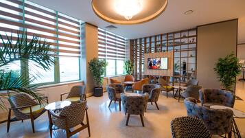 Un espace détente moderne avec des fauteuils à motifs, une table centrale et un écran de télévision.
