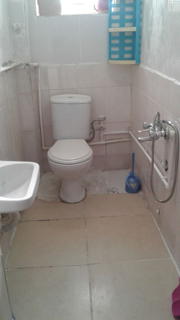Et lille badeværelse med toilet, vask og bruser.