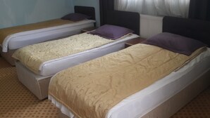 Dos camas individuales con cabeceras, una ventana con cortinas y una alfombra estampada.