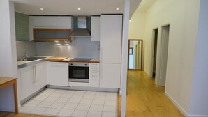 Une cuisine compacte avec des meubles blancs, un four encastré et un plan de travail en bois.