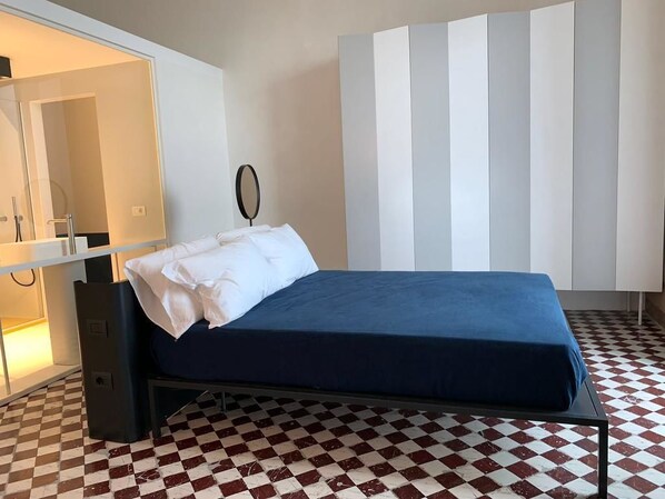 Quarto com cama, espelho, guarda-roupa e chão xadrez.