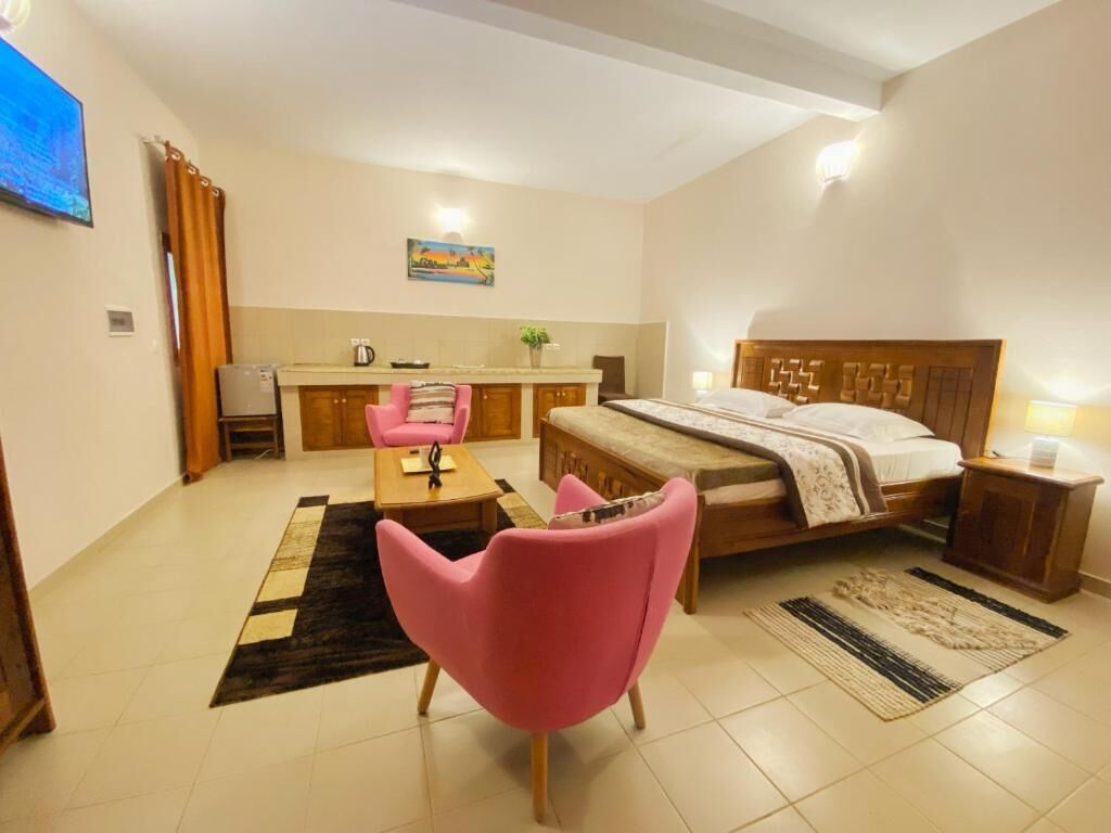 Un dormitorio con cama, escritorio, silla y kitchenette.
