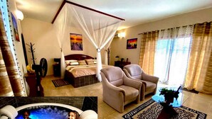 A bedroom with a four-poster bed, a sitting area with two armchairs, a large window with curtains, and a small balcony. - Hôtel La Belle Etoile & SPA (Mbour)