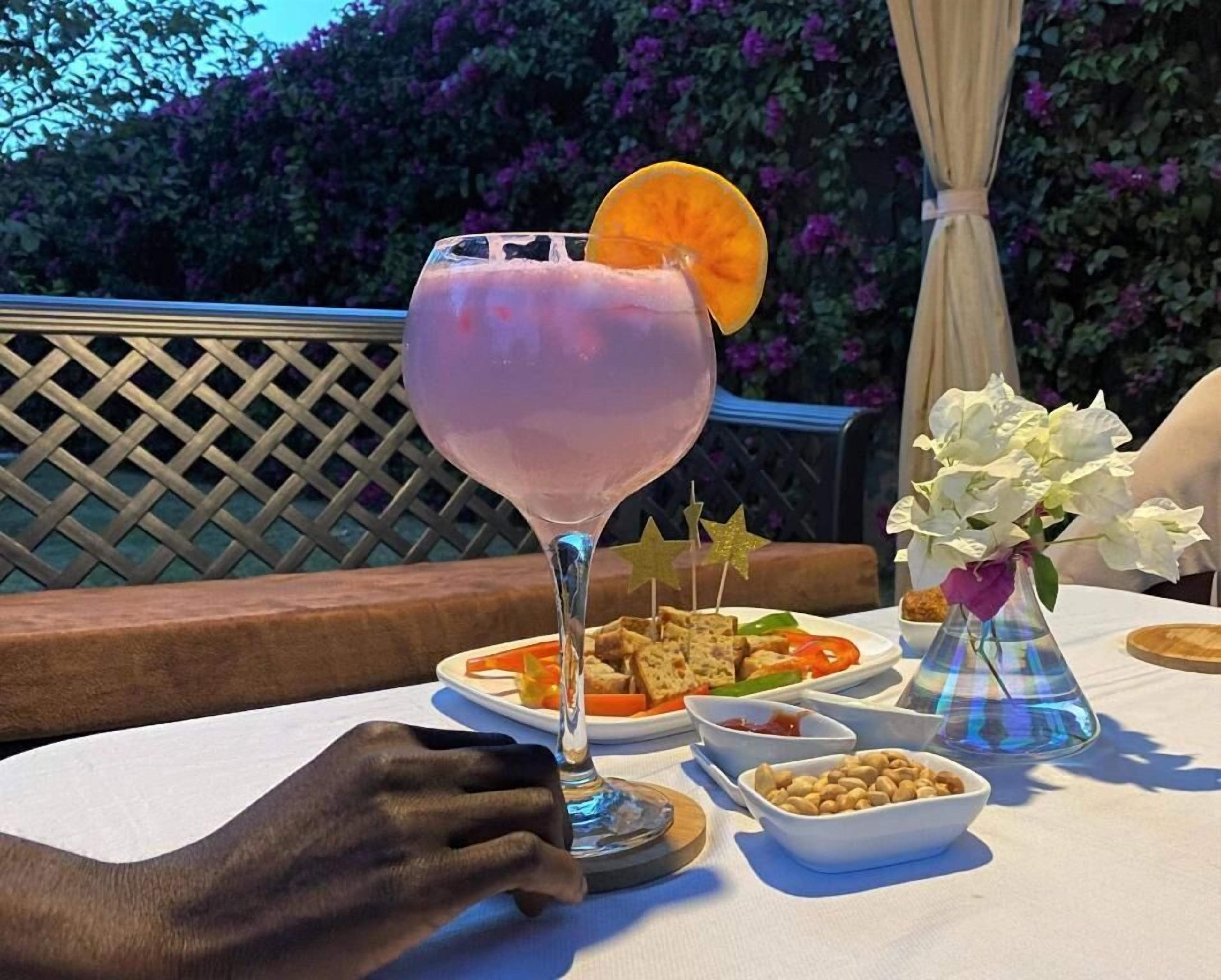 Une table dressée avec une boisson, de la nourriture et un vase de fleurs.