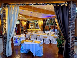 Un salón de banquetes con mesas redondas, manteles blancos y cintas amarillas.