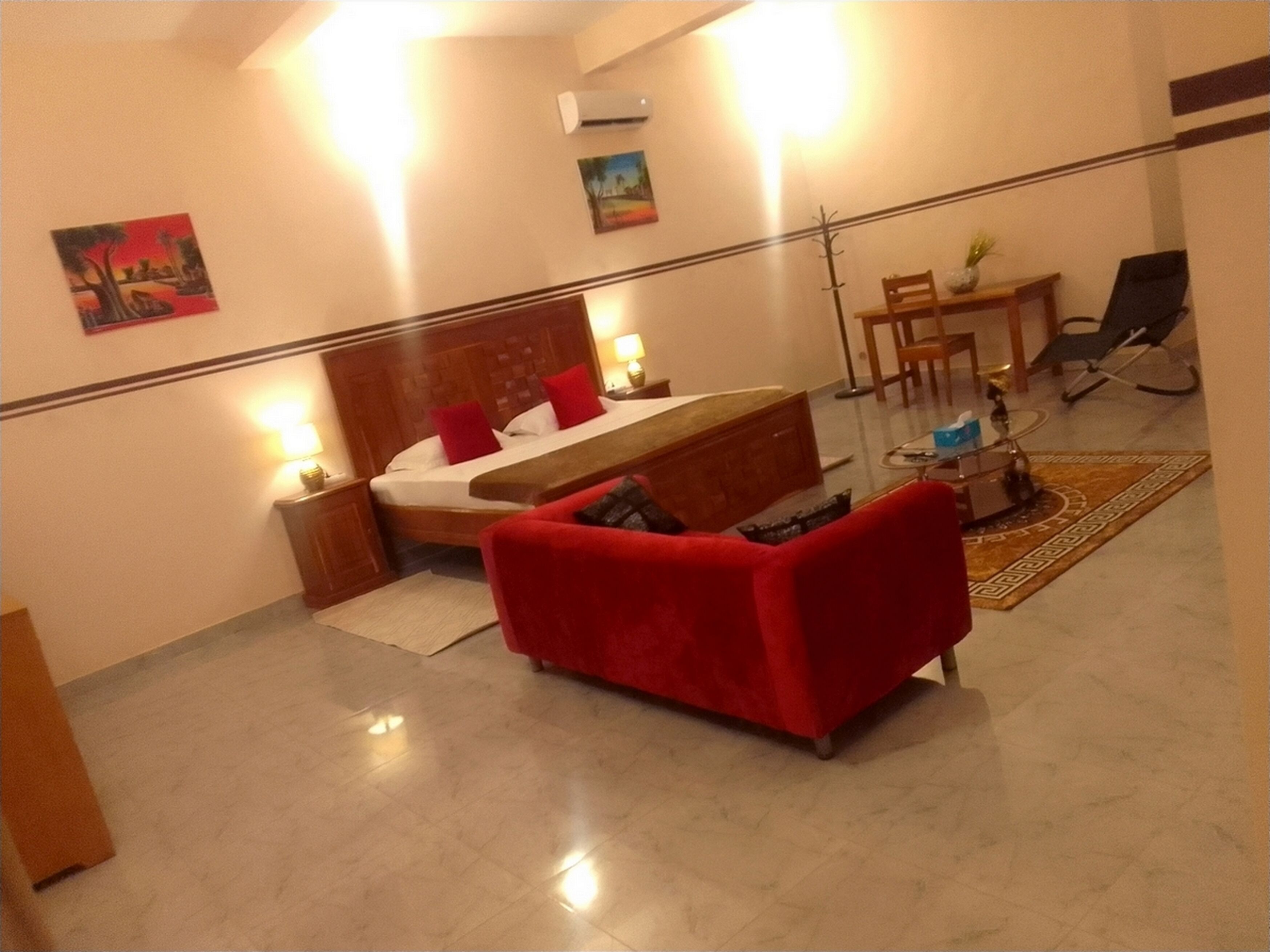 Une chambre d’hôtel avec un lit, un canapé rouge, une petite table et une chaise.