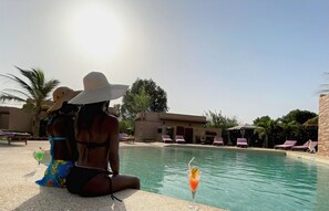 Un espace aménagé au bord de la piscine, avec des chaises longues et un ciel dégagé.