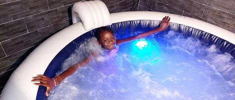 A child in a hot tub with a blue light, surrounded by water.
