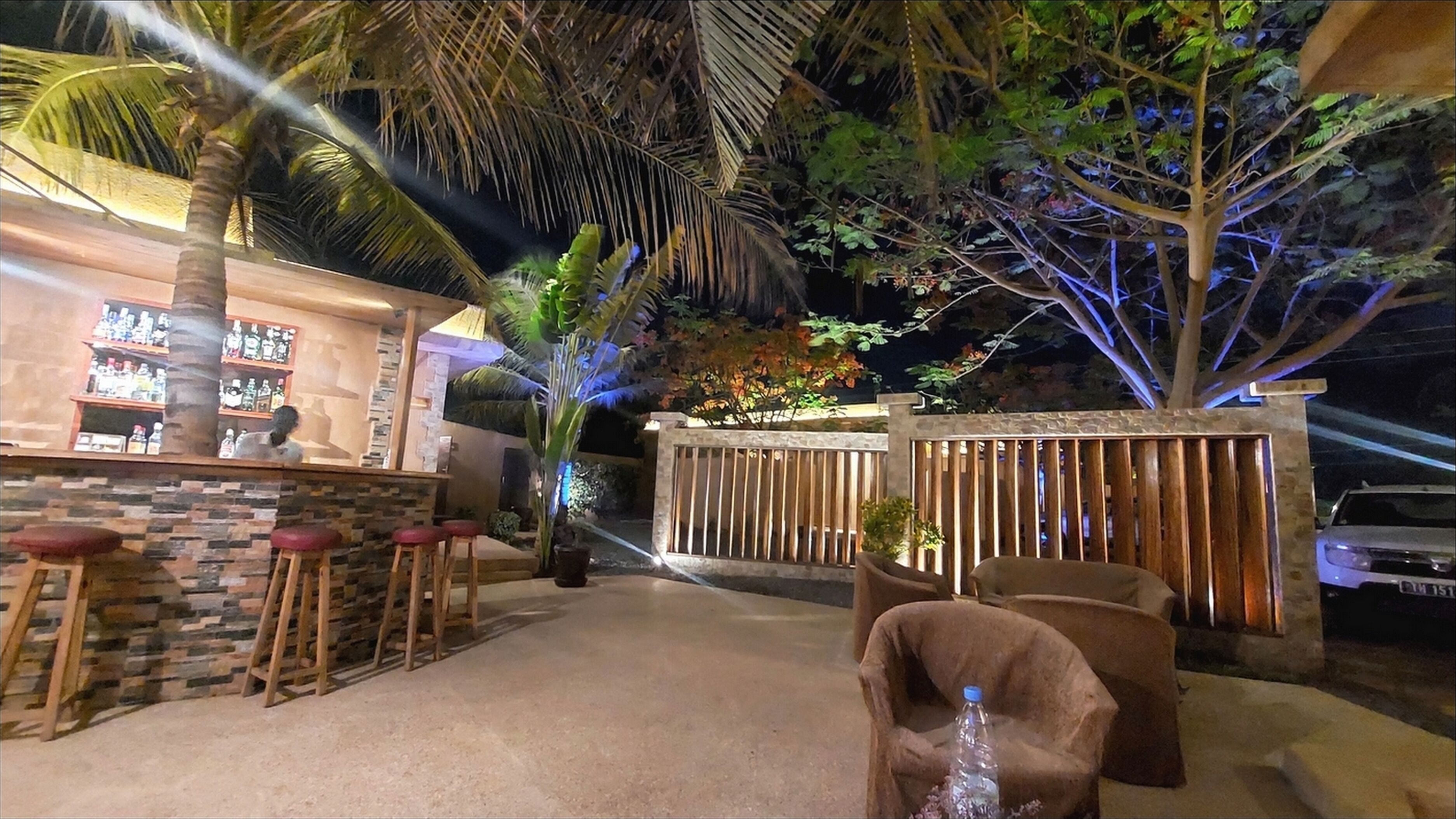 A bar area with stools, a stone wall, and a wooden fence.