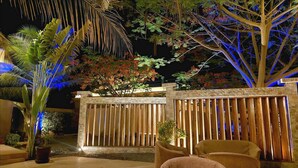 An outdoor area with a stone wall, wooden fence, and seating. - Hôtel La Belle Etoile & SPA (Mbour)
