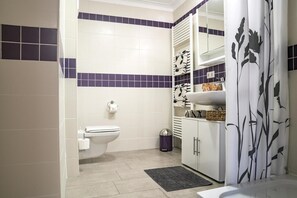 A bathroom with a toilet, sink, and storage cabinets.