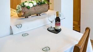 A dining table with a white tablecloth, a bottle of wine, and a decorative planter with flowers.