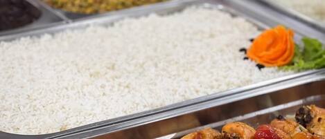 Un bufé con diversos platos, incluyendo arroz, pollo y verduras mezcladas.