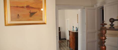 A hallway with a framed painting, a wooden dresser, and a staircase with a wooden balustrade.