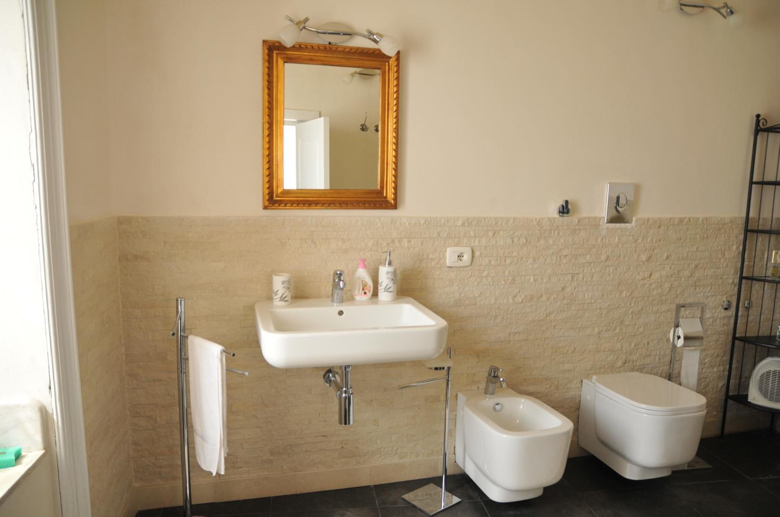 Une salle de bain avec un lavabo blanc, un miroir, un bidet et des toilettes.