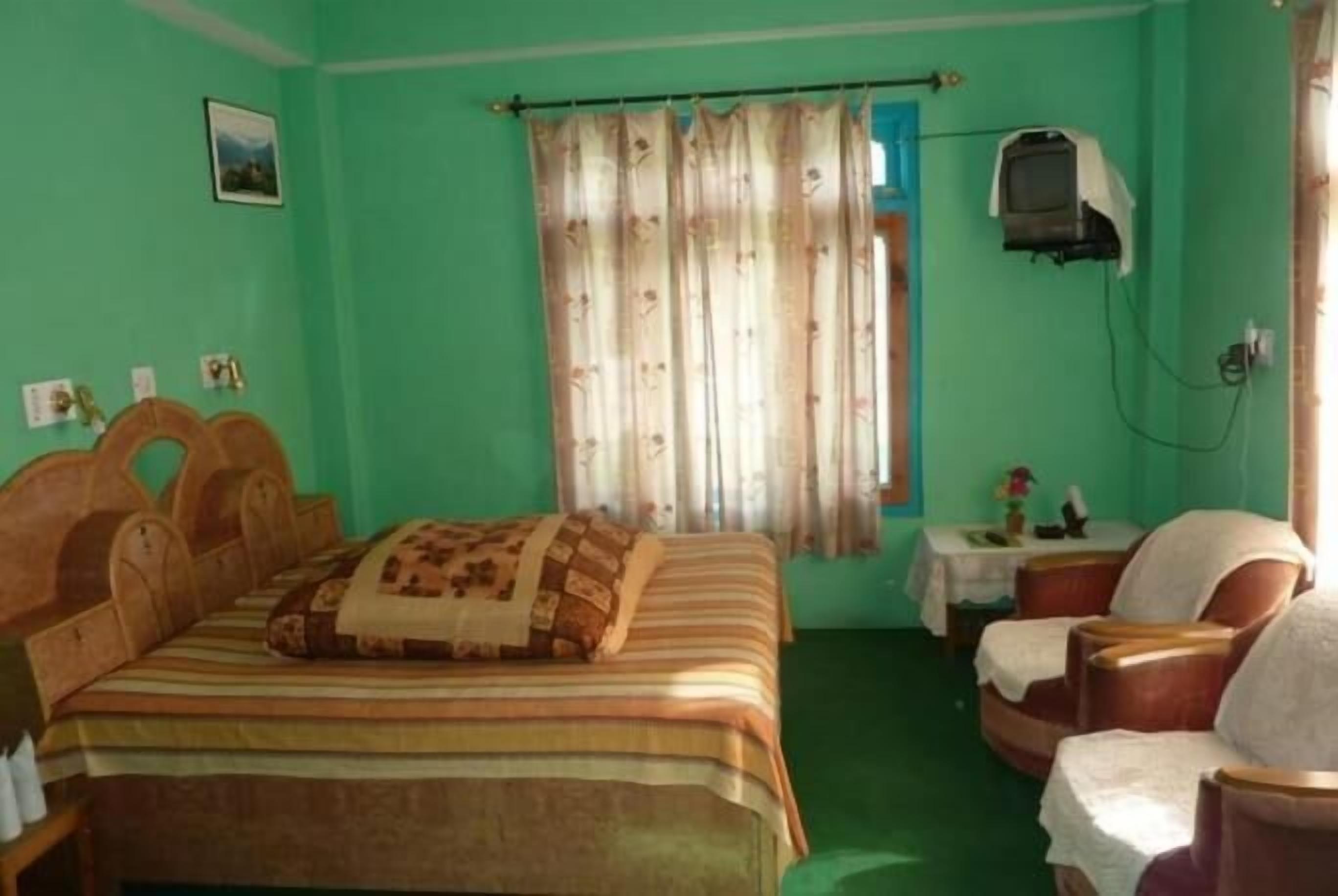 A room with a bed, a chair, a small table, and a television.