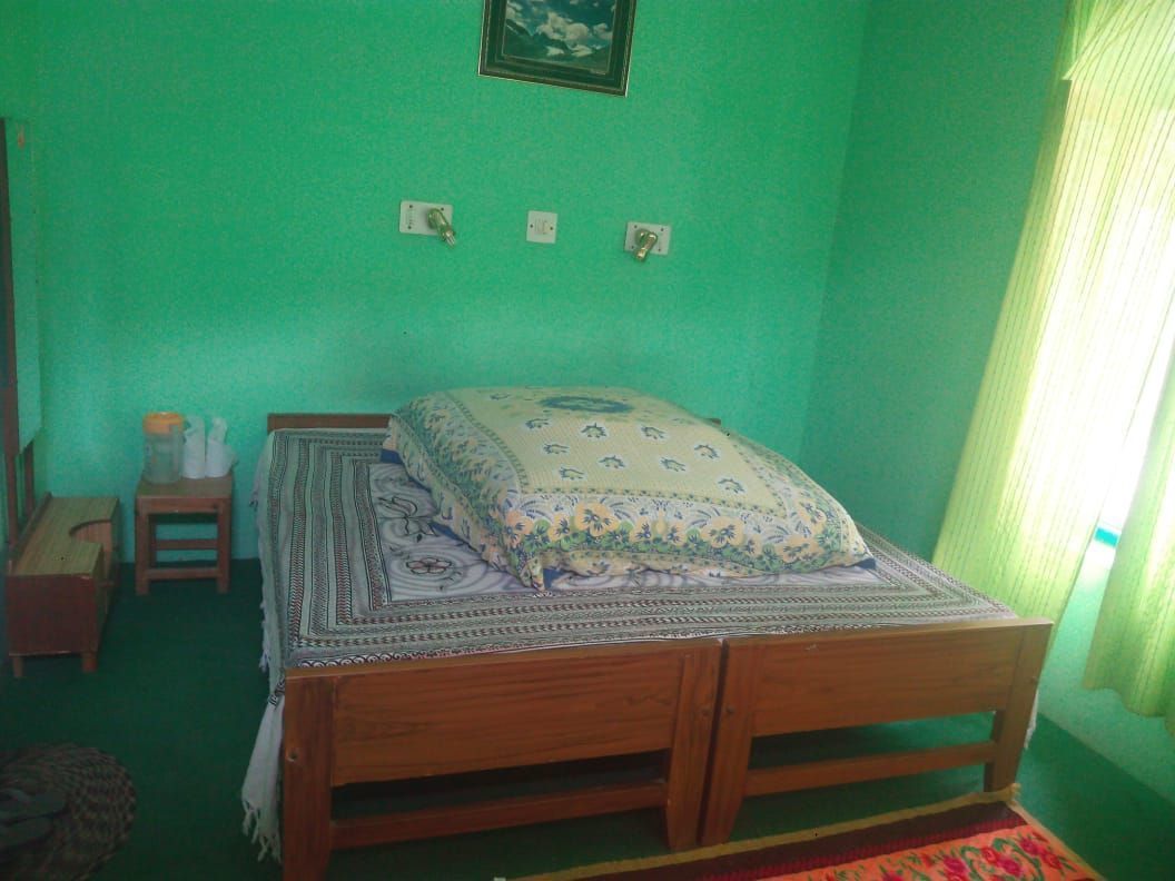 A room with a wooden bed, a small bedside table, and a green wall.