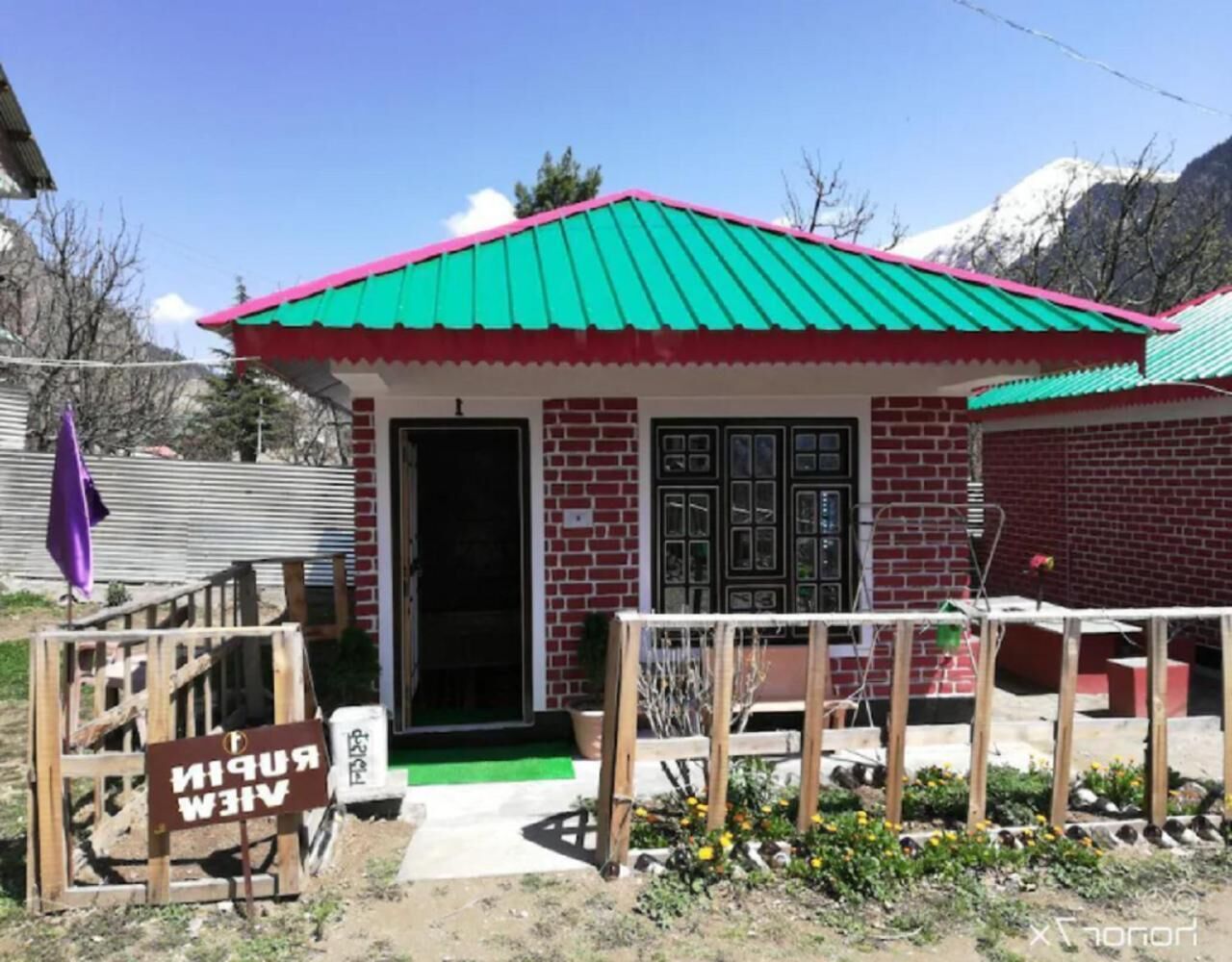 A small brick building with a green roof and a wooden porch.