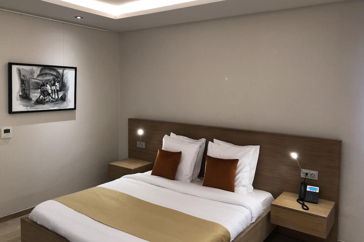 Habitación de hotel moderna con una cama grande, una mesita de noche con teléfono y un cuadro enmarcado en la pared.