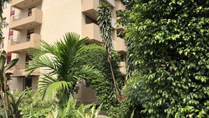 A multi-story building with balconies, surrounded by lush greenery and a variety of plants. - Elais Kinshasa (Kinshasa)