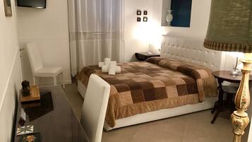 Habitación de hotel con una cama grande, un televisor de pantalla plana montado en la pared, una mesita de noche con lámpara y un cuadro sobre la cama.