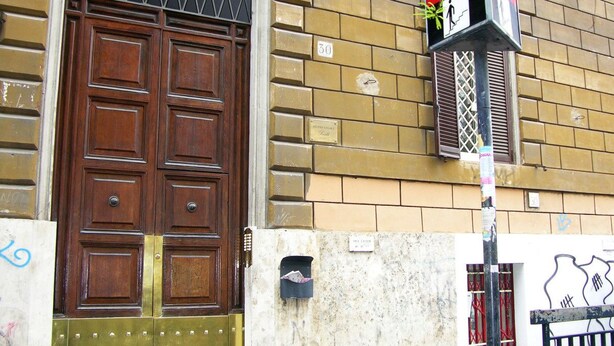 Ein Gebäude mit einer großen Holztür, einem Briefkasten und einem Straßenschild.