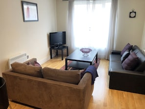 A living room with a sofa, a coffee table, a TV, and a couch.