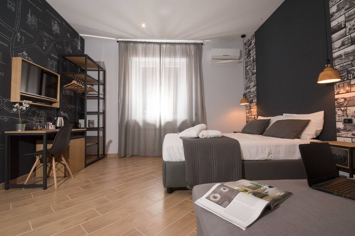 A modern bedroom with a bed, bedside table, and a desk with a chair.