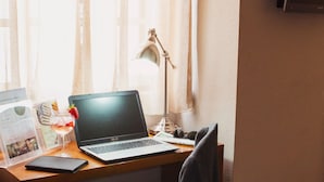 A wooden desk with a laptop, a lamp, and a glass with a straw and a strawberry. - Hotel Império do Rei (Castelo Branco)