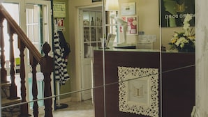 A hotel reception area with a check-in counter, a chandelier, a staircase, and a mirror reflecting the interior. - Hotel Império do Rei (Castelo Branco)