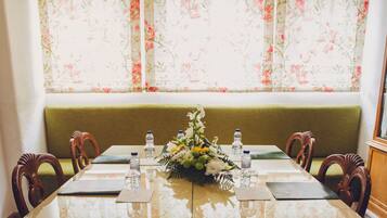 Une table à manger dressée avec des bouteilles d’eau, un centre de table floral et un banc recouvert d’un tissu vert.