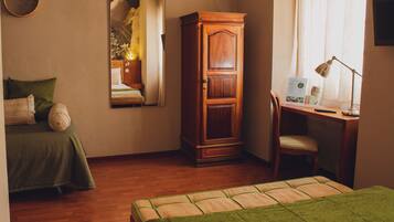 Een kamer met een bed, bureau, stoel, kledingkast en spiegel.