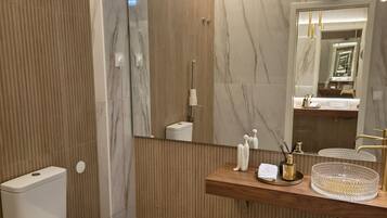 A modern bathroom with a toilet, sink, and mirror.