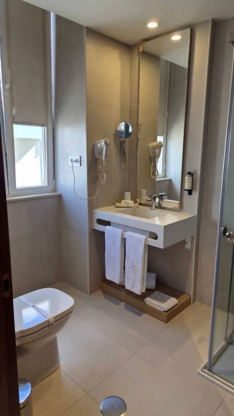A modern bathroom with a toilet, a sink with a mirror, and a shower area.