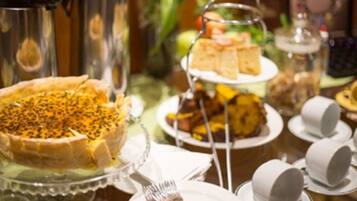 A buffet table with various dishes, including a pie with seeds on top, a cake on a stand, and several cups and plates.